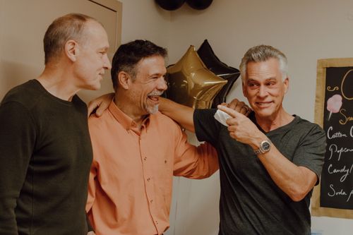 Free Three mature men celebrating together with balloons, sharing joyful moments indoors. Stock Photo