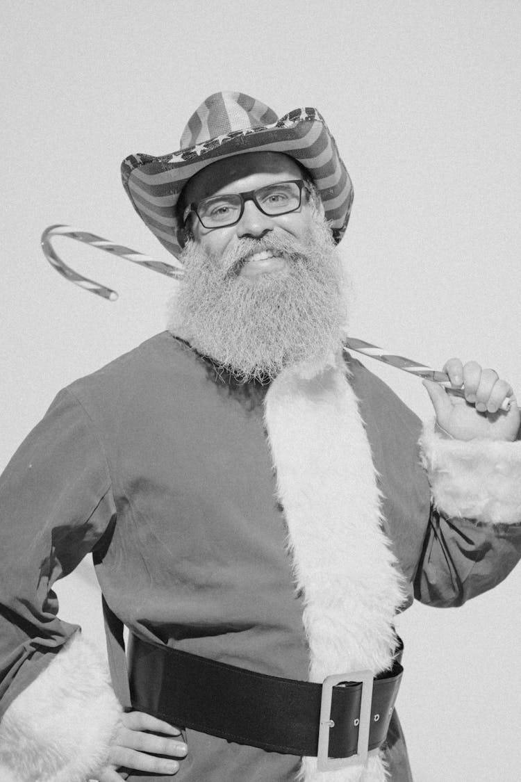 Senior Bearded Man In Santa Costume And Cowboy Hat In Studio