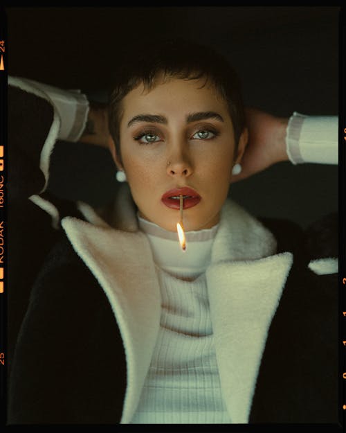 Model in Sweater and Jacket Posing with Burning Match