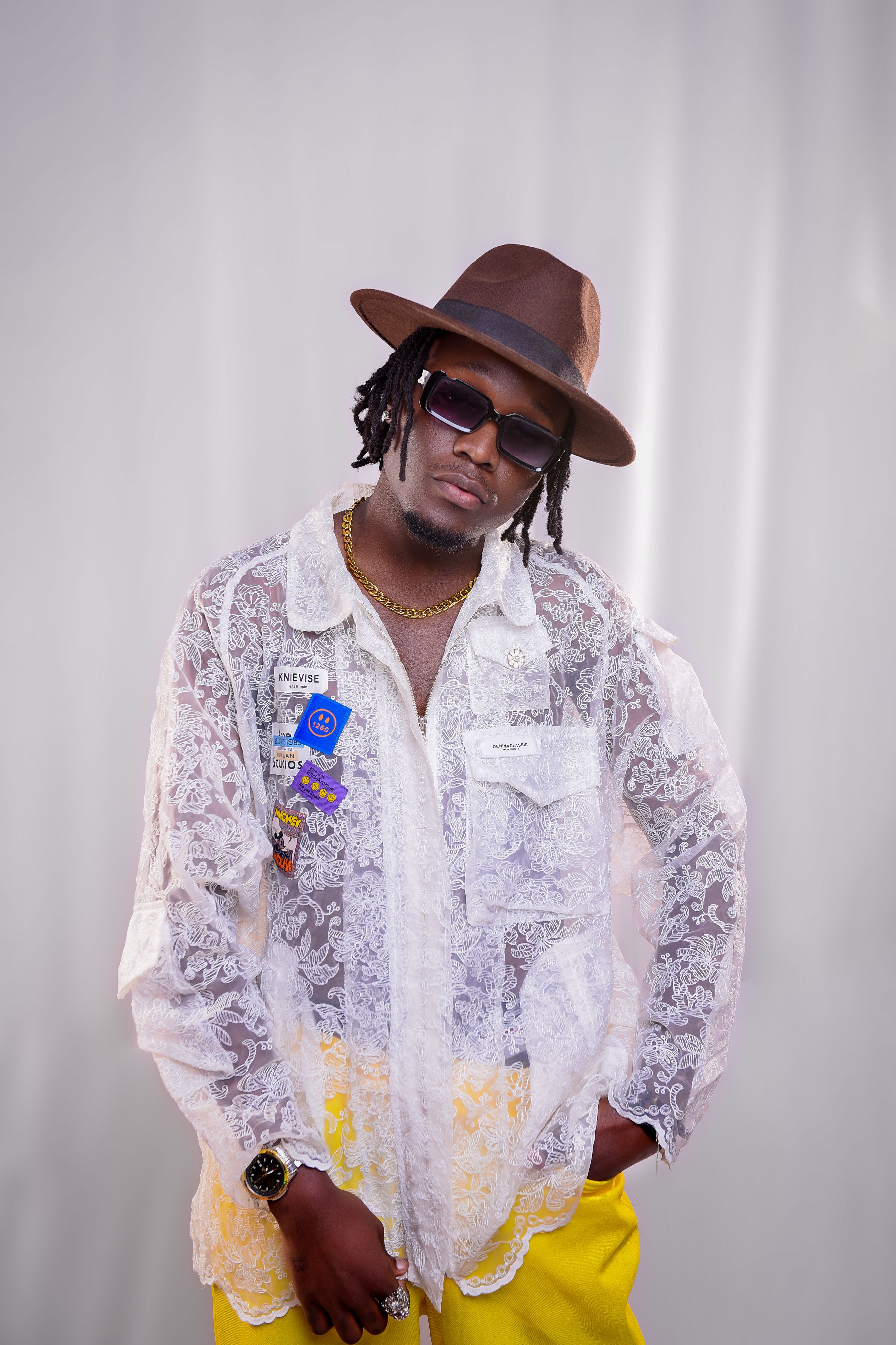 Elegant portrait of a fashionable African man in a stylish outfit and hat, set in a studio.