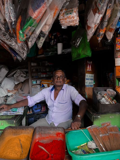 Free Vendor in an Indian market stall with vibrant spices and goods on display. Stock Photo