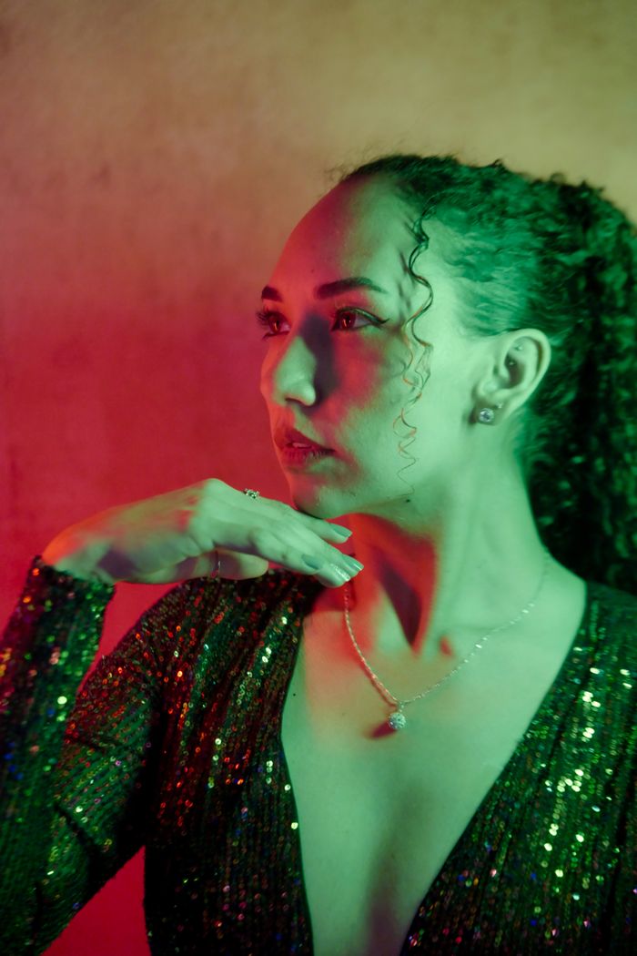 Guest in a dark sequin gown in dramatic coloured light