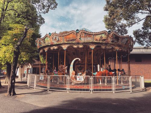 Free Charming old-fashioned carousel in a Kumamoto park, evokes nostalgia with vibrant colors. Stock Photo