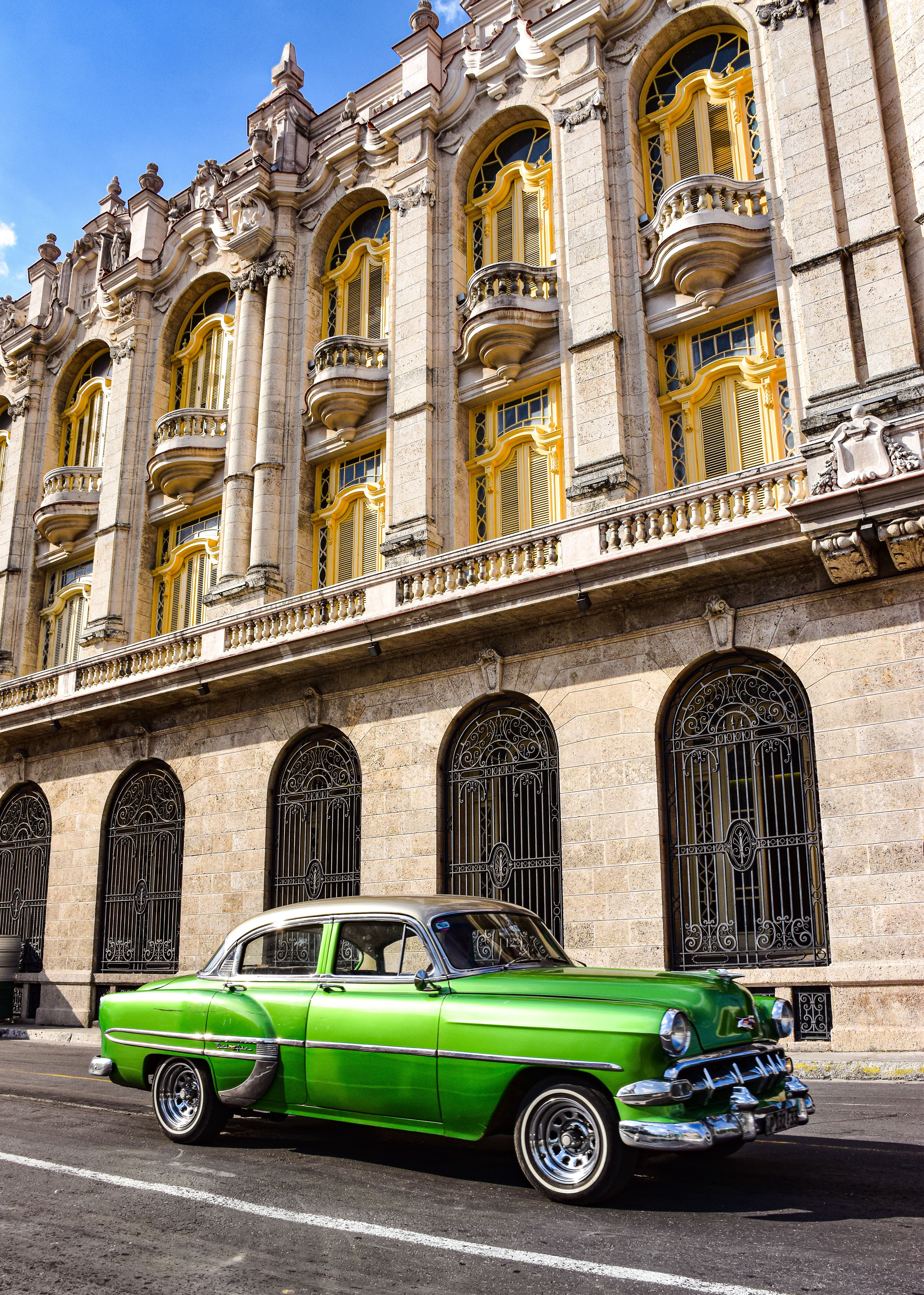 Classic green Chevrolet parked in front of a historic building in Havana, Cuba.