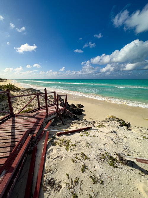 Free Beautiful beach view with turquoise waters and rustic broken wooden pathway. Stock Photo