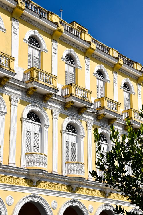 Free Elegant yellow building with classical architecture and ornate details on a sunny day. Stock Photo