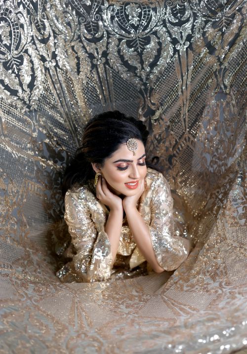 Free A woman posing elegantly in a shimmering traditional golden outfit, exuding grace and beauty. Stock Photo