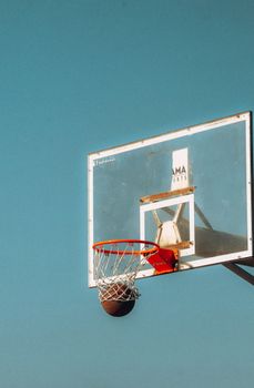 A basketball hoop with net and ball captured against a clear blue sky. Perfect for sports themes.