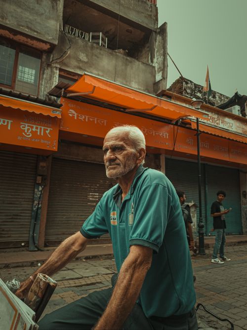 Free Elderly man with stubble in an urban Indian street, vibrant storefronts behind. Stock Photo