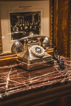 Classic vintage rotary telephone on a marble surface with a black and white photo backdrop, indoor setting.