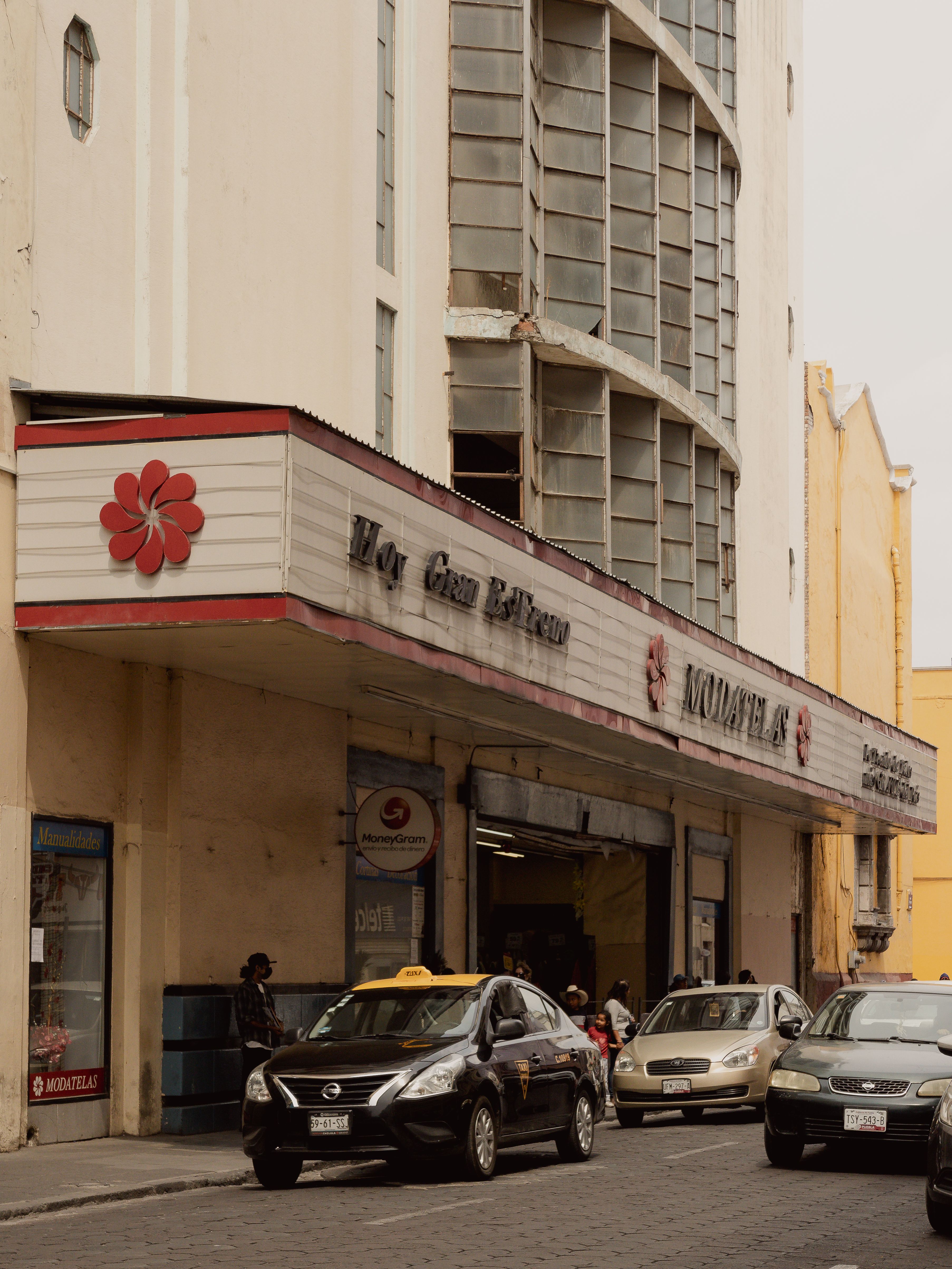Street view of a historic theater building facade with urban traffic in Puebla, Mexico.