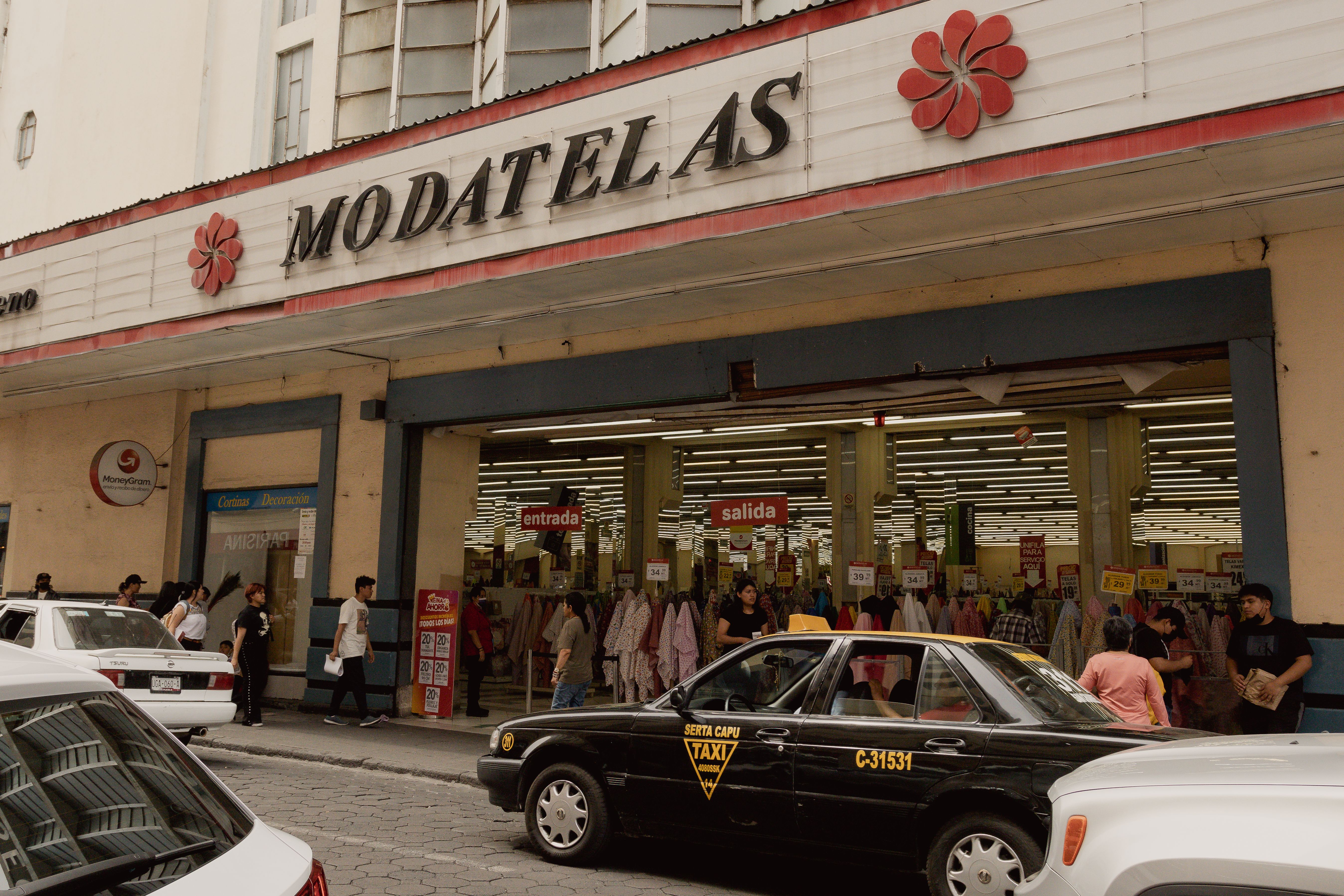 Street scene in Puebla, Mexico featuring people, cars, and a Modatelas store.