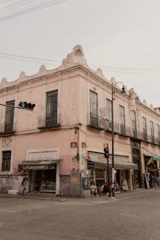 Charming colonial architecture on a busy corner in Puebla, Mexico, with local shops and pedestrians.
