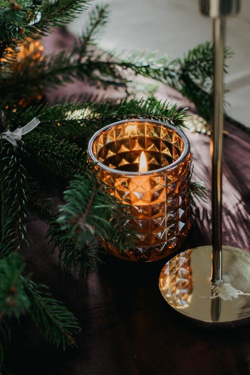 Free Warm candle glow surrounded by festive evergreen branches, creating an elegant Christmas ambiance. Stock Photo