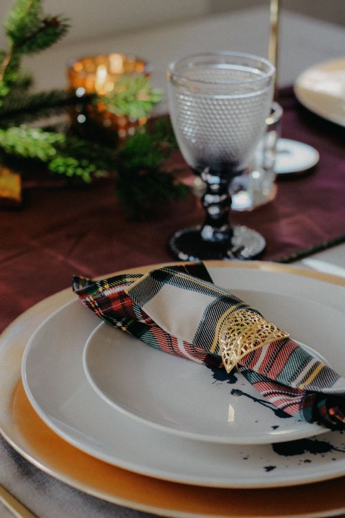 Free A festive table setting with plaid napkin and glass, perfect for holiday celebrations. Stock Photo