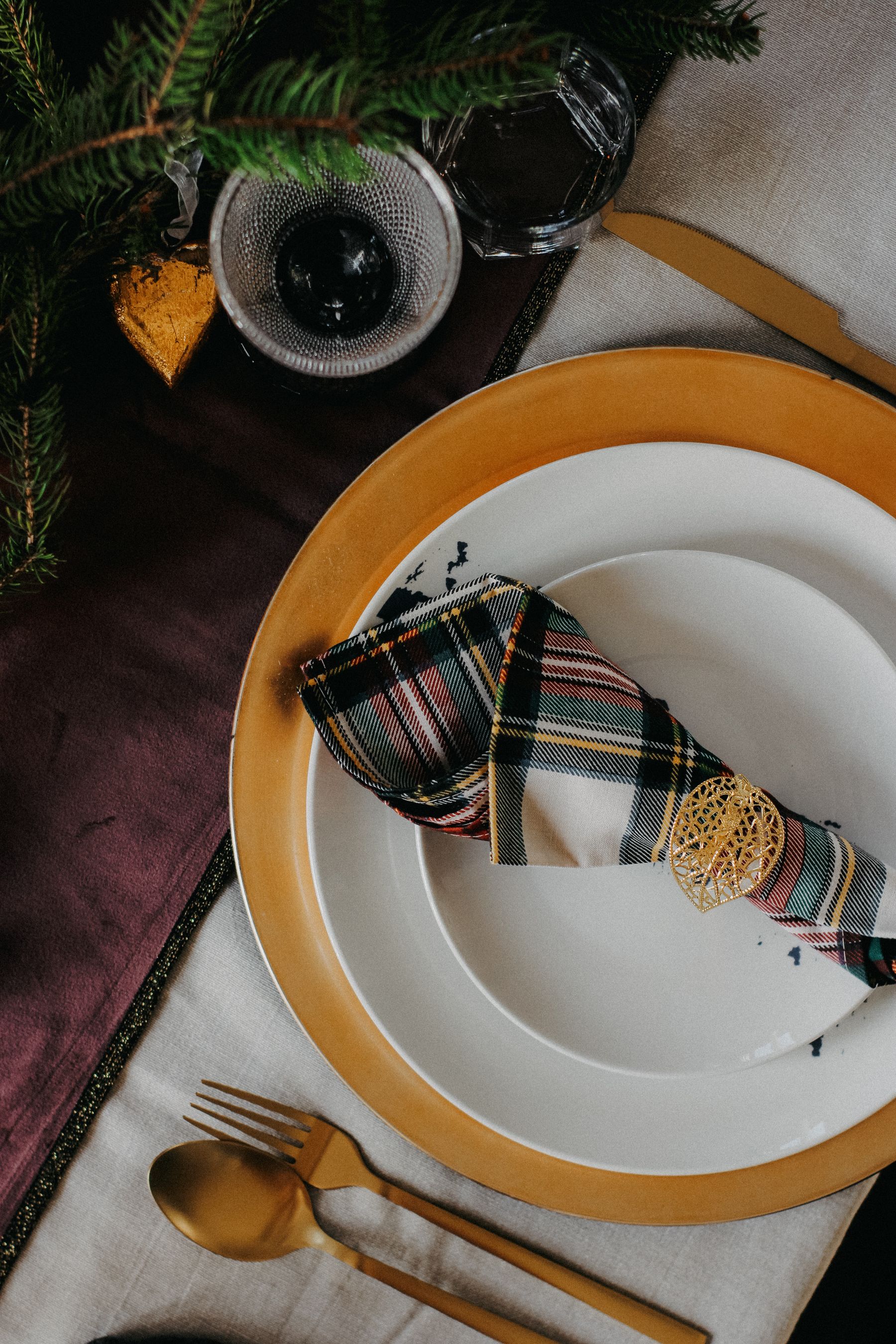Holiday place setting with plaid napkin and greenery