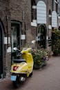 迷人的街道上，停着一辆充满活力的黄色滑板车，两旁是经典的砖砌建筑和鲜花