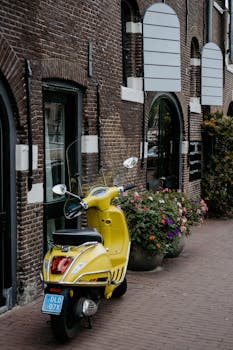 迷人的街道上，停着一辆充满活力的黄色滑板车，两旁是经典的砖砌建筑和鲜花