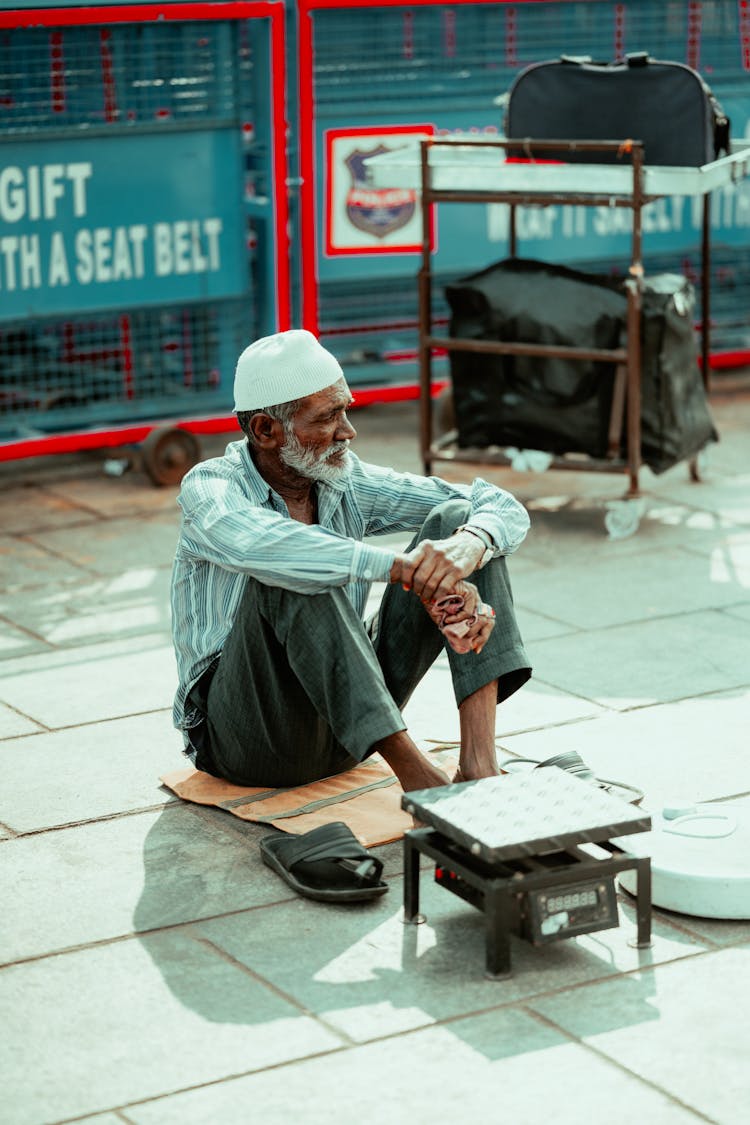 Man Sitting On Sidewalk