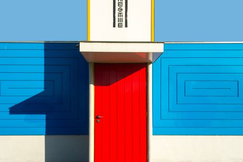 Free Colorful architectural detail of a vibrant red door set against a geometric blue wall in urban Rotterdam. Stock Photo