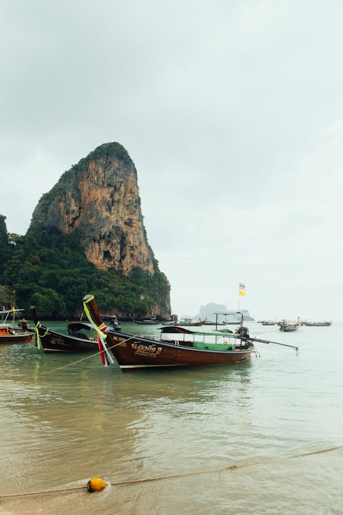 View of Boats Moored on the Shore near a Rocky Cliff 