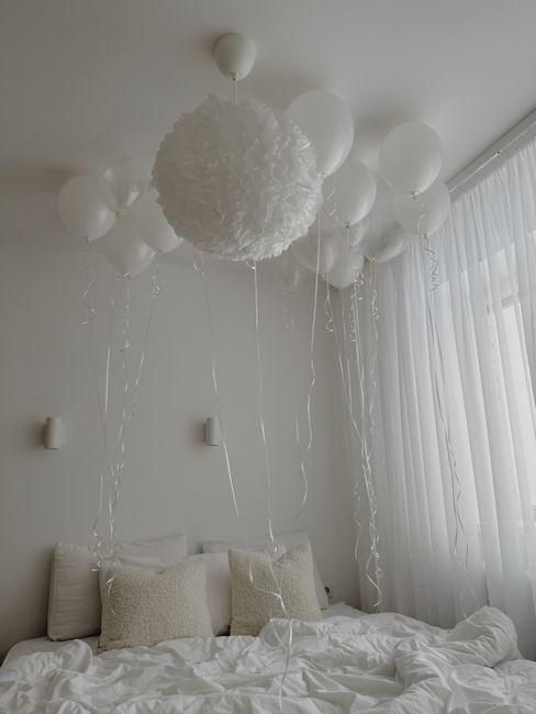 Serene white bedroom featuring elegant balloon decor and soft lighting for a calming atmosphere.