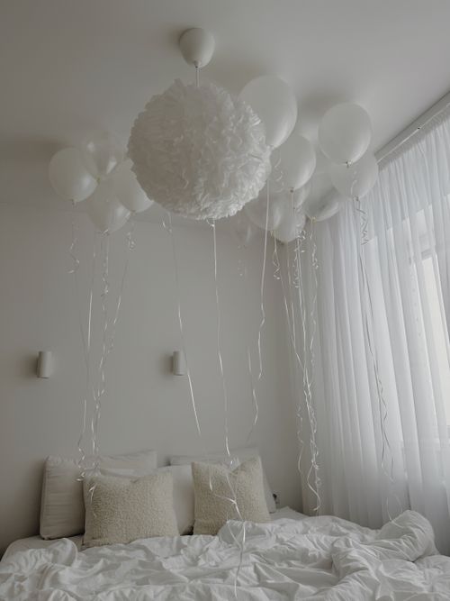 Free Serene white bedroom featuring elegant balloon decor and soft lighting for a calming atmosphere. Stock Photo