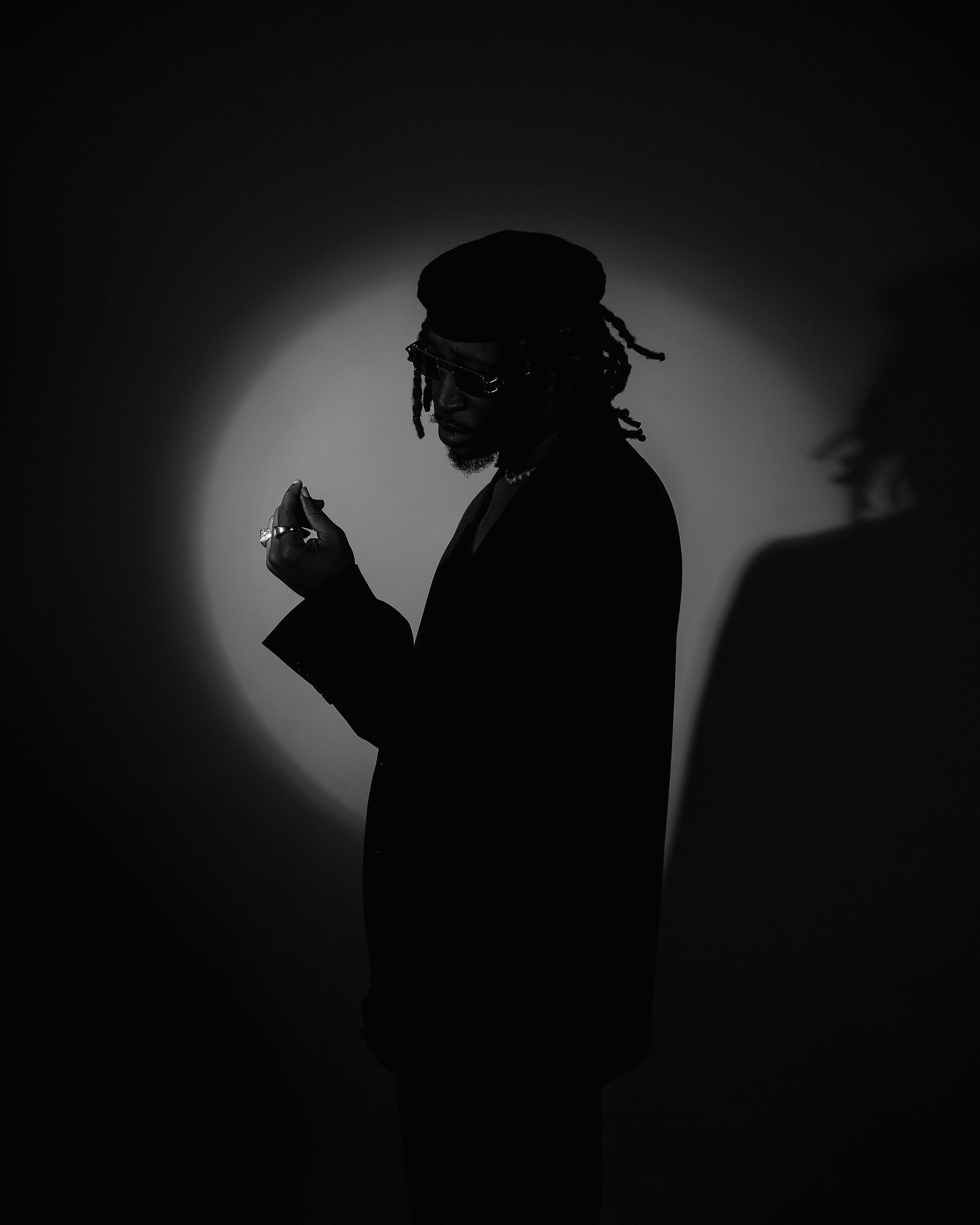 Captivating black and white portrait of a man with dreadlocks, showcasing dramatic lighting and silhouette.
