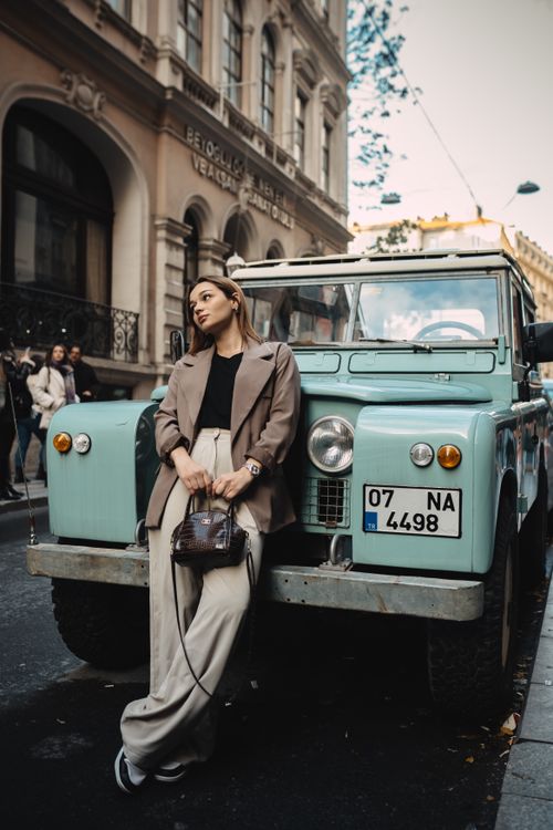 Free Fashionable woman poses with a mint green vintage truck on a city street, embodying retro urban style. Stock Photo