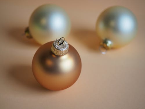 Free Three gold and silver christmas ornaments on a beige background Stock Photo