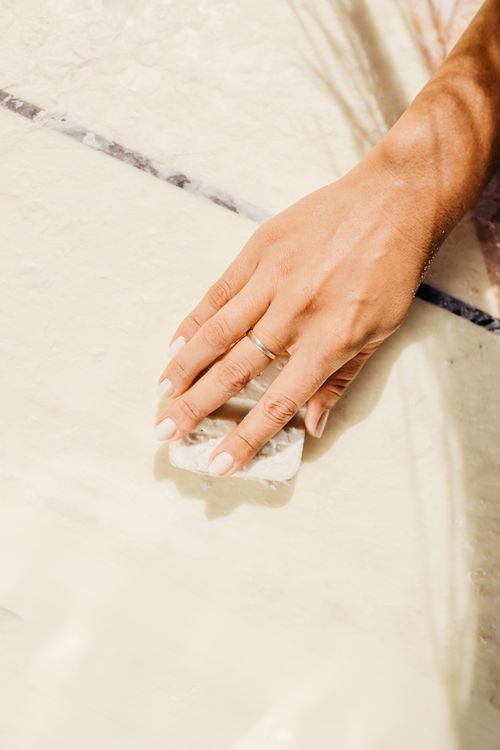 Free A woman's hand with a wedding ring resting on a surfboard in bright summer light. Stock Photo