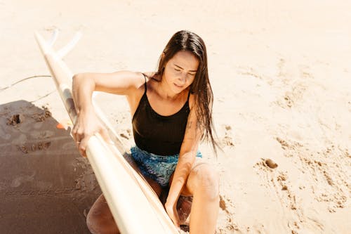 Brunette Woman Sitting with Surfboard