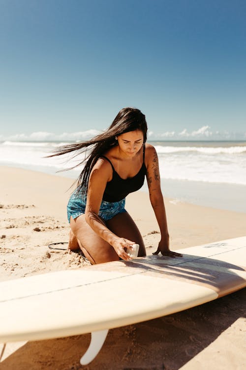 Young Woman Waxing a Surfboard