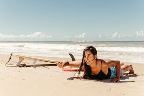 Woman Lying on the Beach next to a Surfboard 