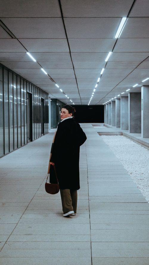 Free A stylish woman in a black coat walking through a modern corridor in Tekirdağ, Türkiye. Stock Photo