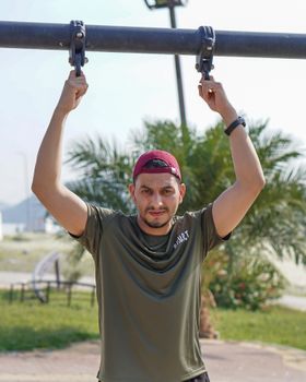 Man hanging on exercise bars in Makkah, Saudi Arabia on a sunny day.