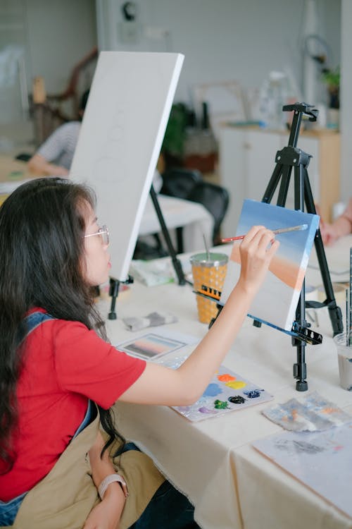 Candid Photo of a Woman Painting a Picture on Canvas 