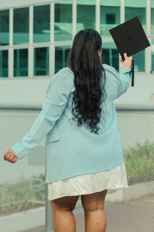 Back View of Woman in Blue Suit Standing and Holding Academic Hat