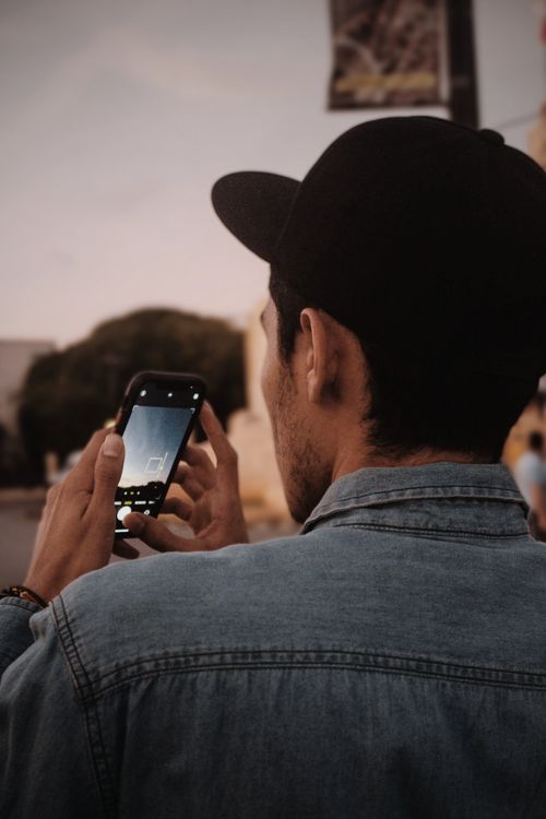 Free Casual man captures urban evening scene with smartphone in Mérida, Mexico. Stock Photo