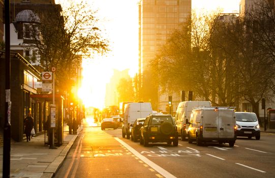 Vibrant city street scene with traffic during a golden sunset, capturing urban life.