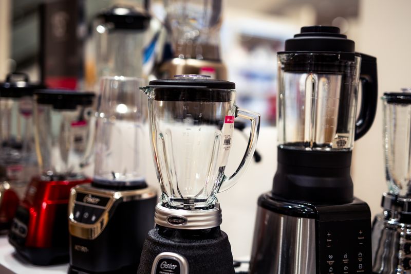 A variety of kitchen blenders displayed on a showroom countertop.