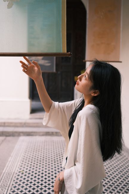 Asian woman gracefully interacting with an art piece in a Hanoi gallery.