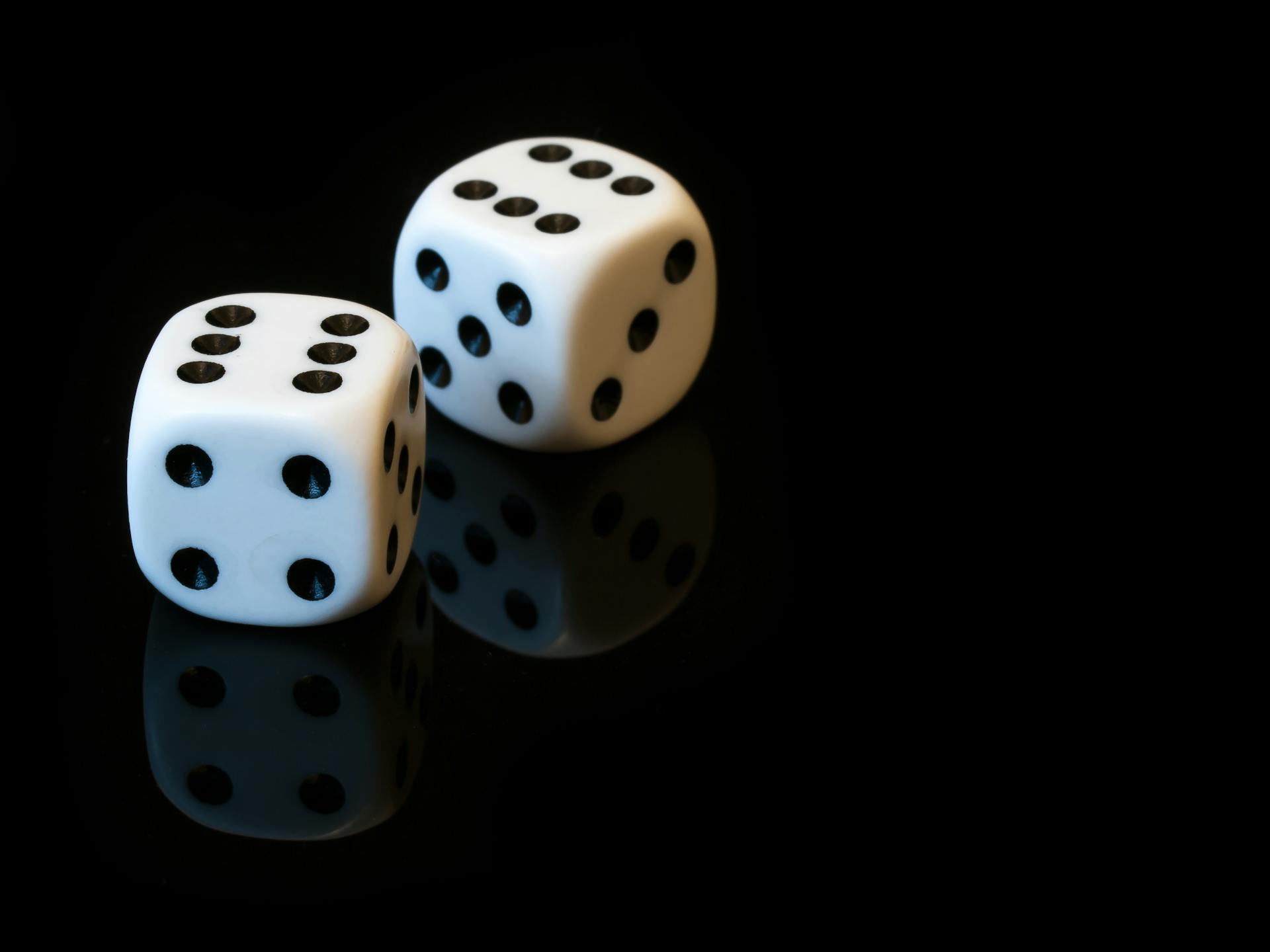 A close-up of two white dice with double sixes on a reflective black surface, perfect for gaming themes.