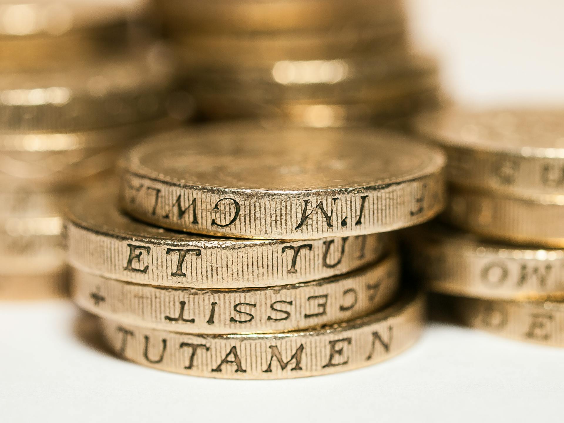 Close-up of stacked British pound coins with engraved text, representing wealth and finance.