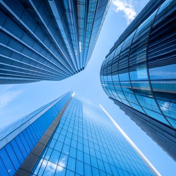 Striking upward view of modern skyscrapers against a clear London sky, showcasing urban architectural elegance.
