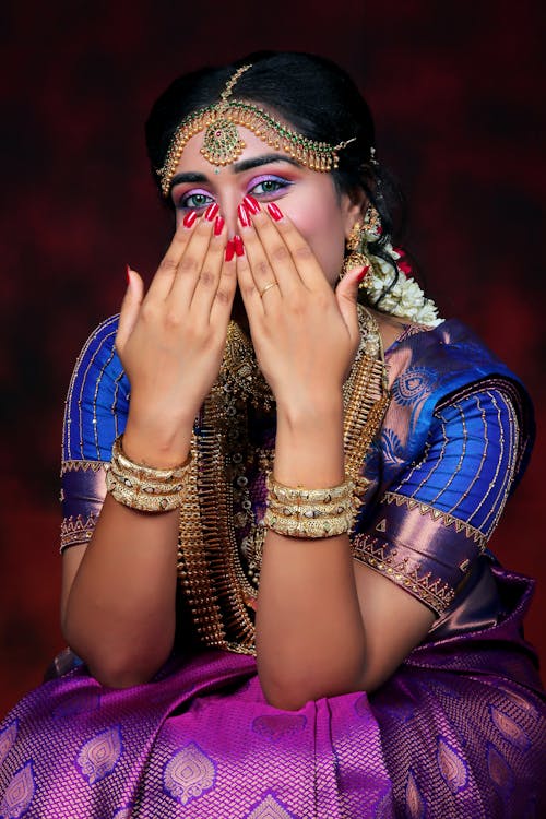 Woman Sitting in Traditional Clothing and with Hands on Face