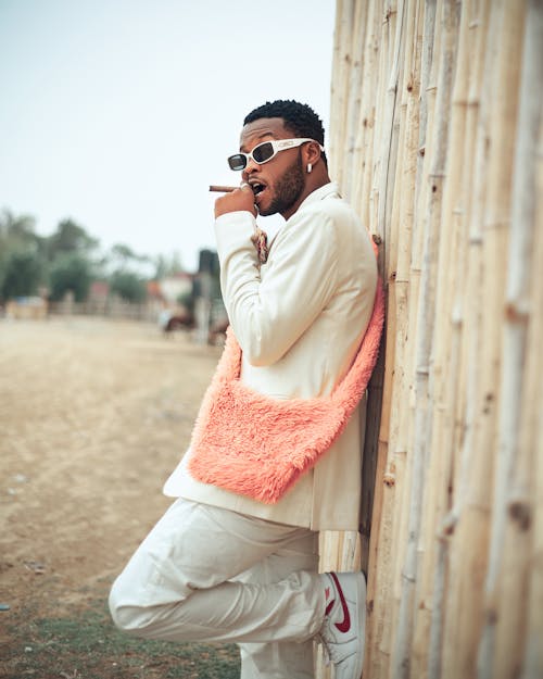 Man in Sunglasses and with Bag Standing by Wall