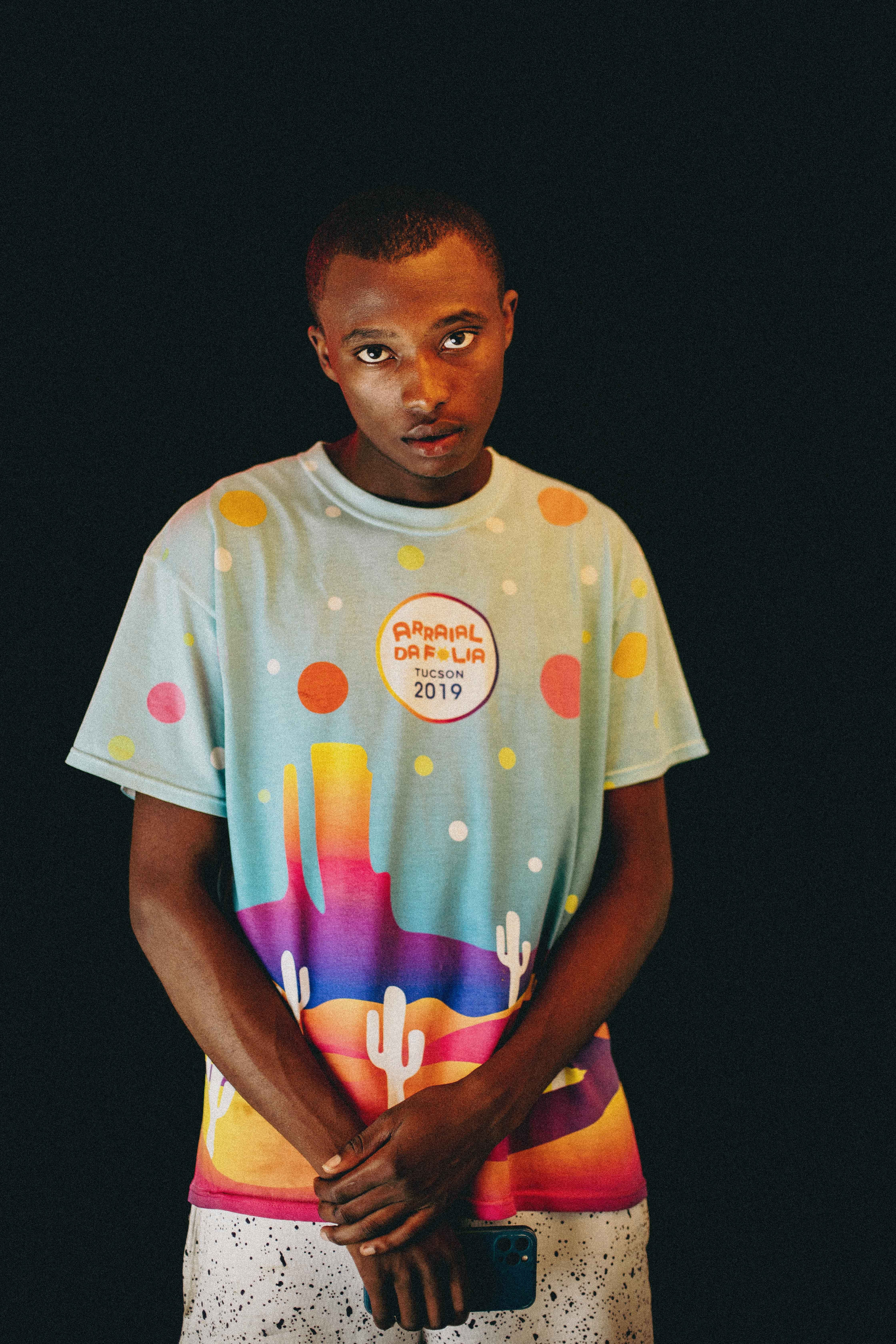 Portrait of a young man in a vibrant t-shirt against a dark background.