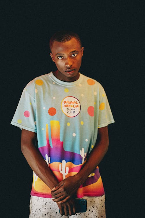 Young Black Man in Colorful T-Shirt Posing on Black Background