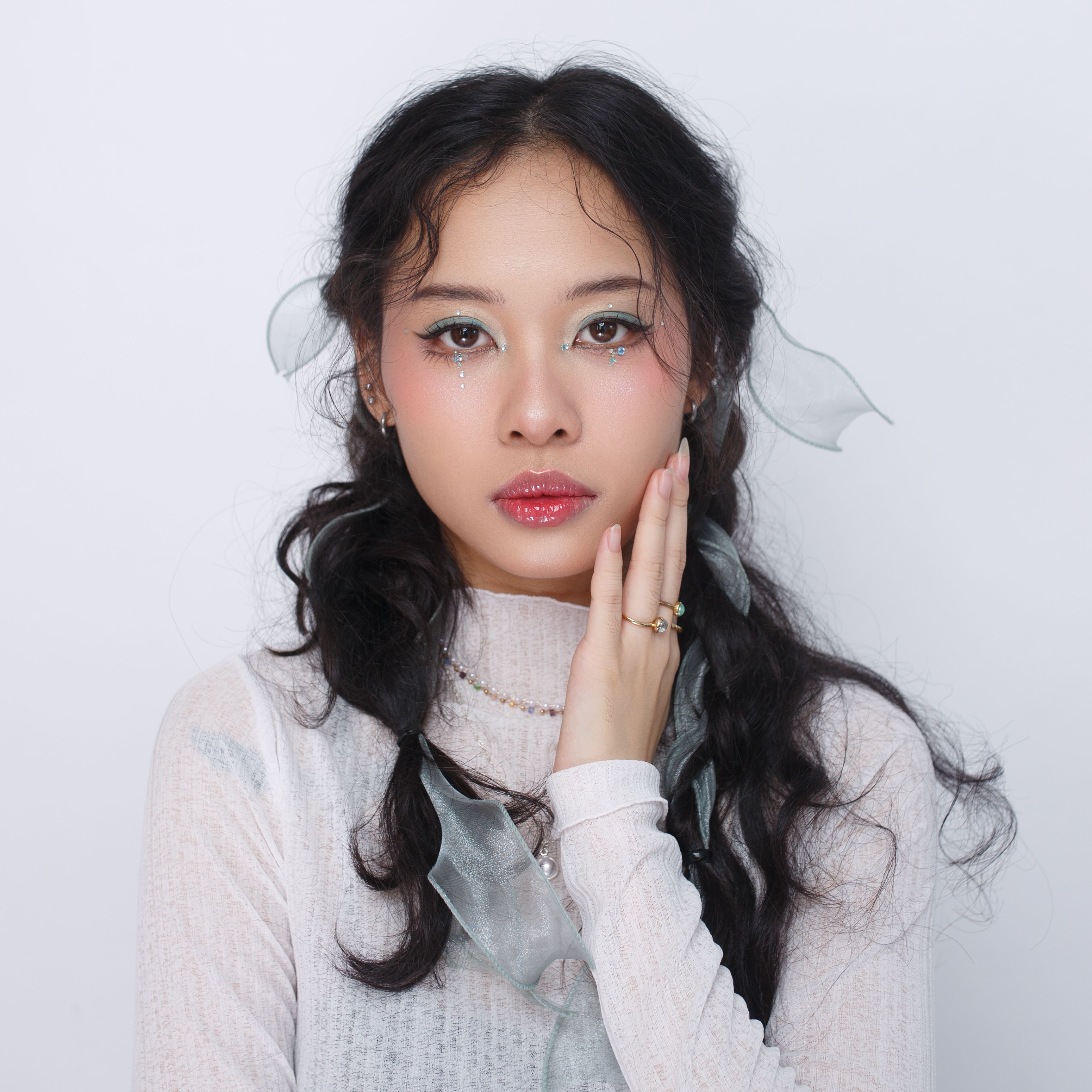 Fashion portrait of an Asian woman with elegant styling and makeup on a white background.